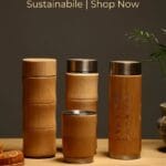 Insulated water bottle wrapped in natural bamboo with a stainless steel lid on a wooden surface