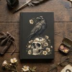 Gothic raven perched on a skull with thorny roses hardcover journal on a dark vintage wooden desk